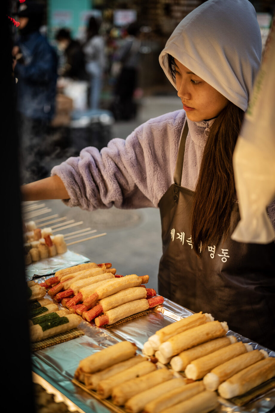 ライカM10-Pとアポ・ズミクロンM f2/50mmで韓国・明洞の出店で串焼きをする女性を撮影した写真